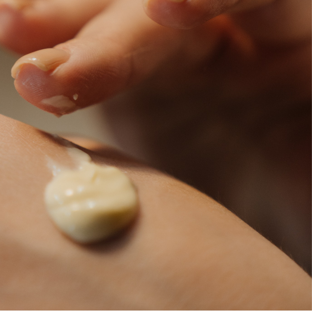 Pregnant woman applying cocoa body butter to nourish and hydrate her skin.